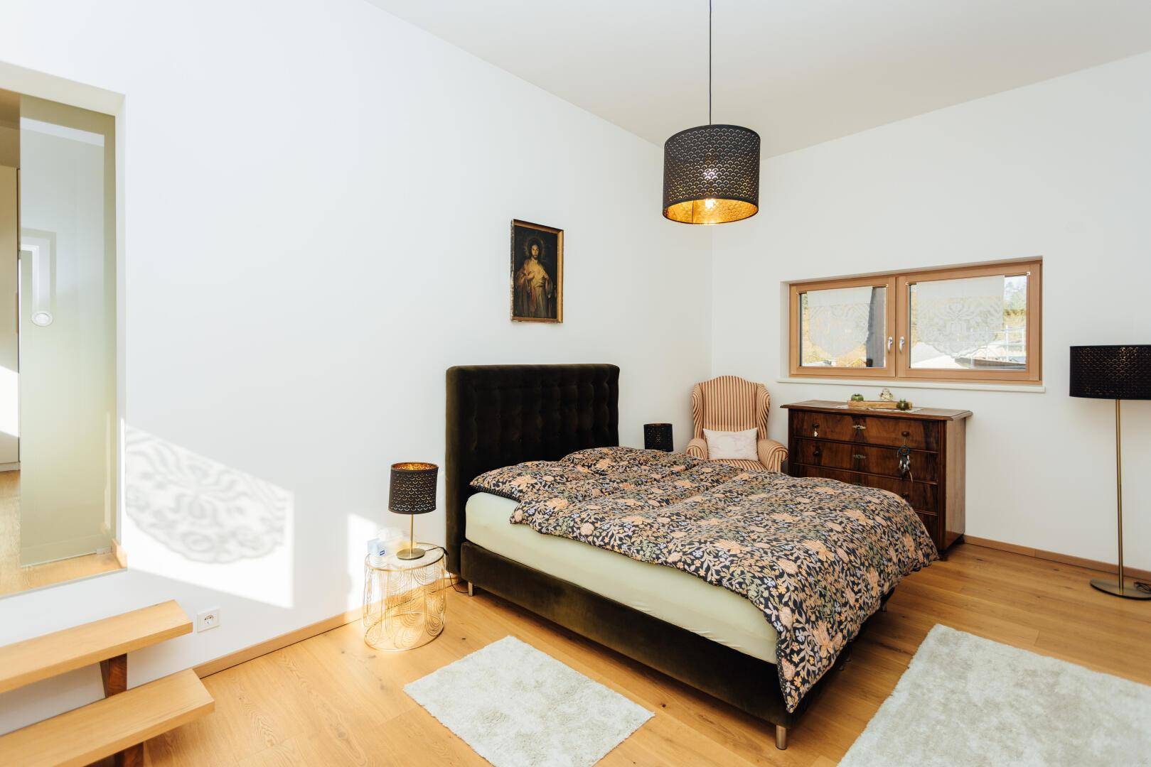 Schlafzimmer mit Holzboden, Doppelbett und Fenster mit Blick ins Grüne.