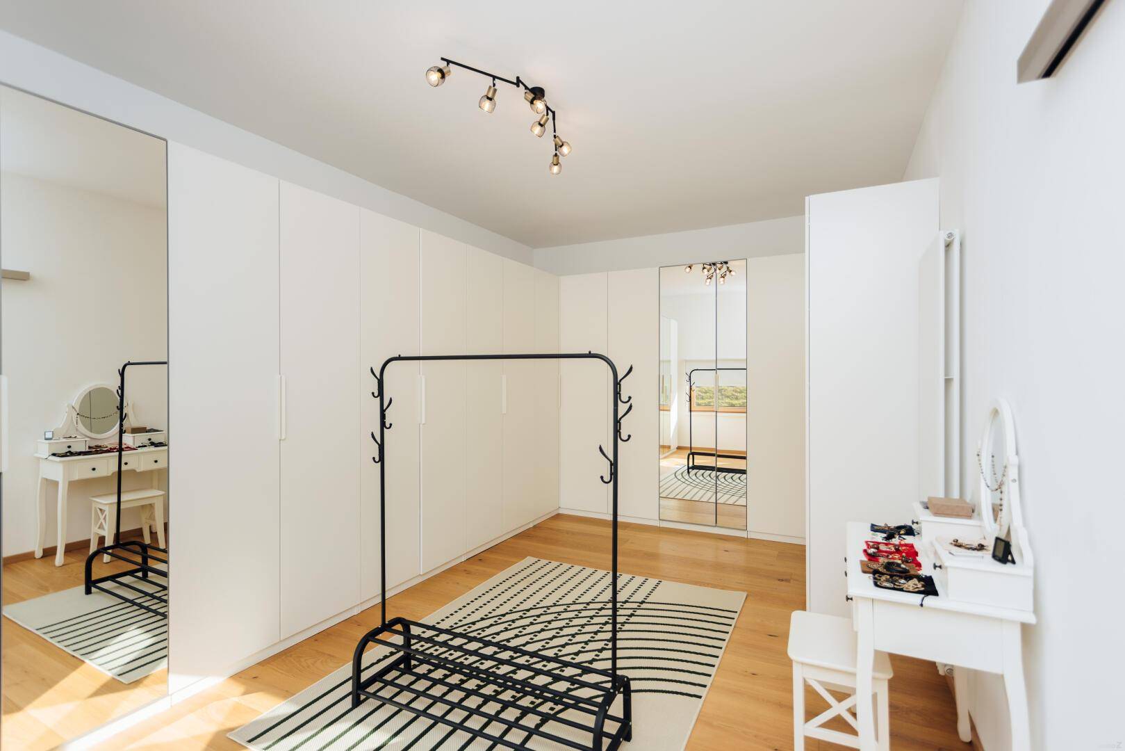 Ankleidezimmer mit Einbauschränken, Spiegeln und Holzboden.