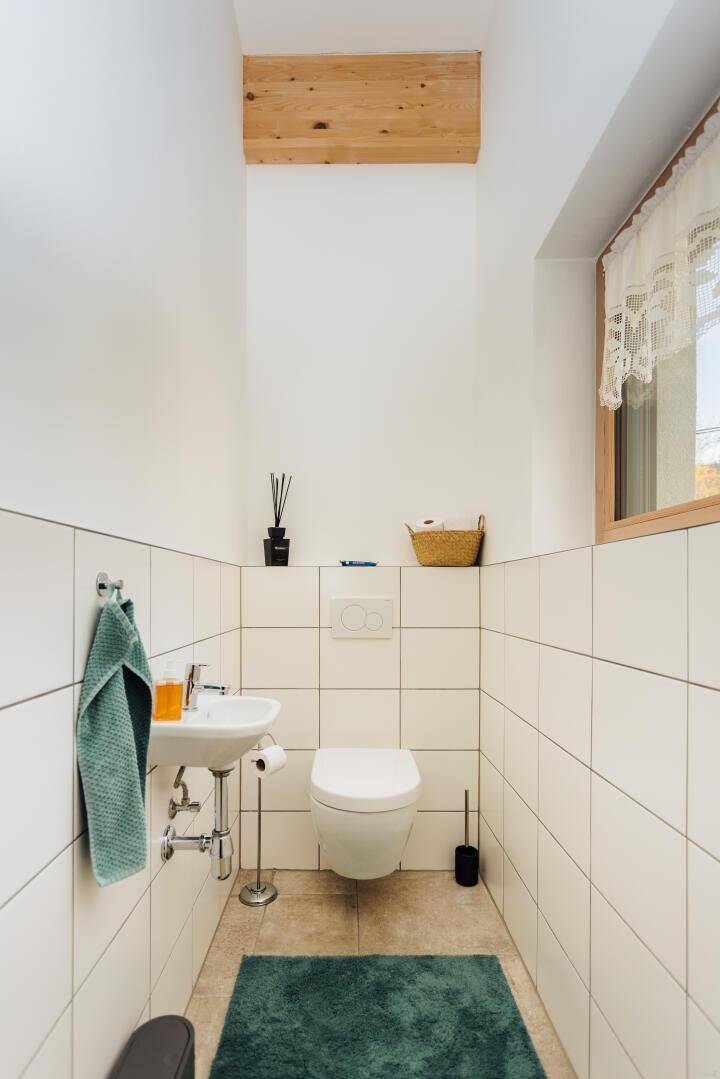 Kleines Gäste-WC mit Wand-WC, Waschbecken und Fliesen.