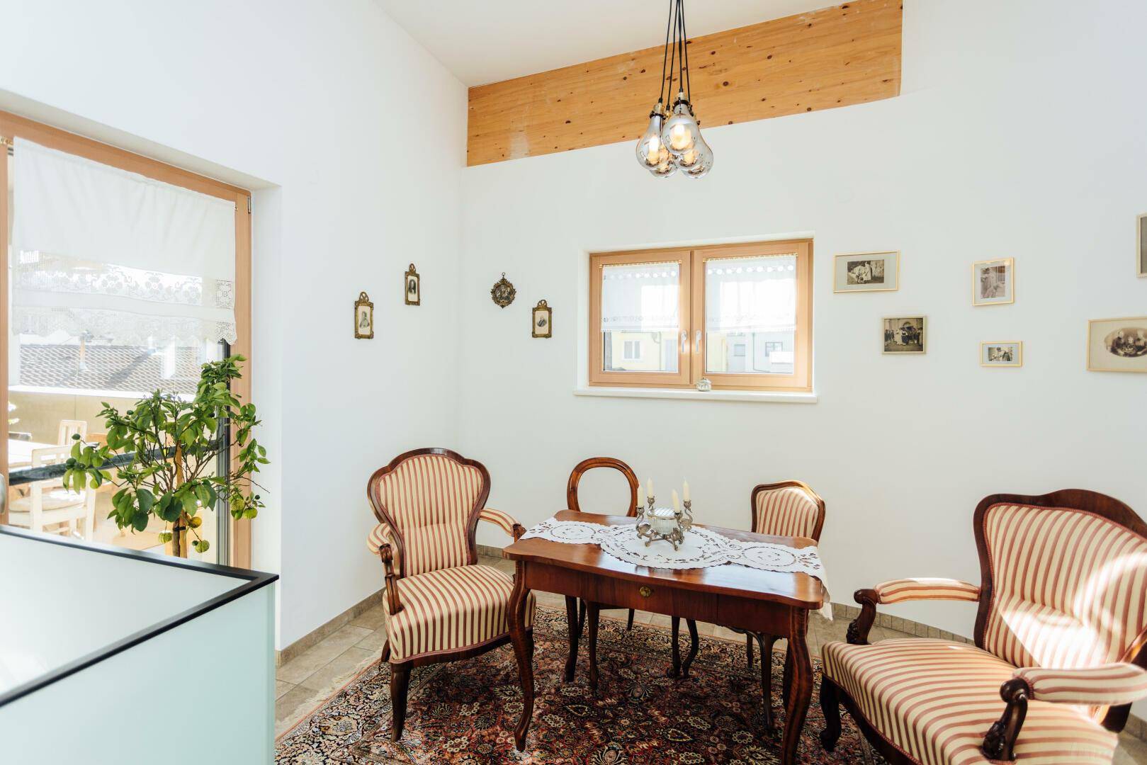 Kleiner Essbereich mit traditionellen Stühlen, Holztisch und Blick ins Grüne.