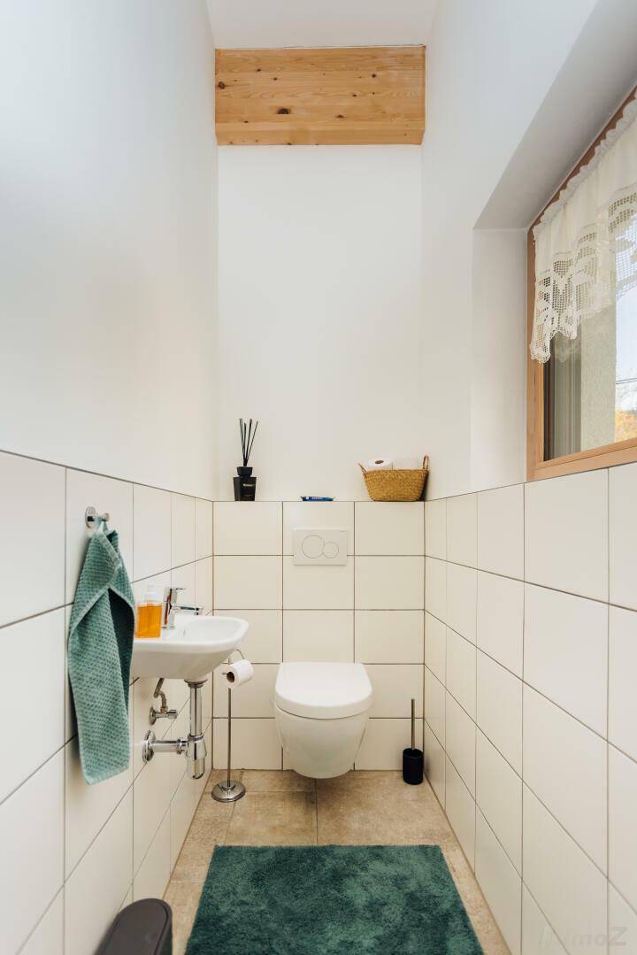 Kleines Gäste-WC mit wandhängendem WC, Waschbecken und Fenster.