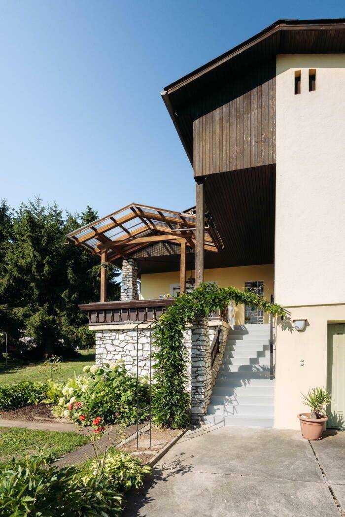 Eingangsbereich des Hauses mit Steintreppe, überdachtem Vorbau und gepflegter Bepflanzung.
