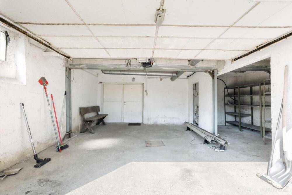 Geräumige Garage mit Betonboden und Stauraum für Fahrzeuge und Werkzeuge.