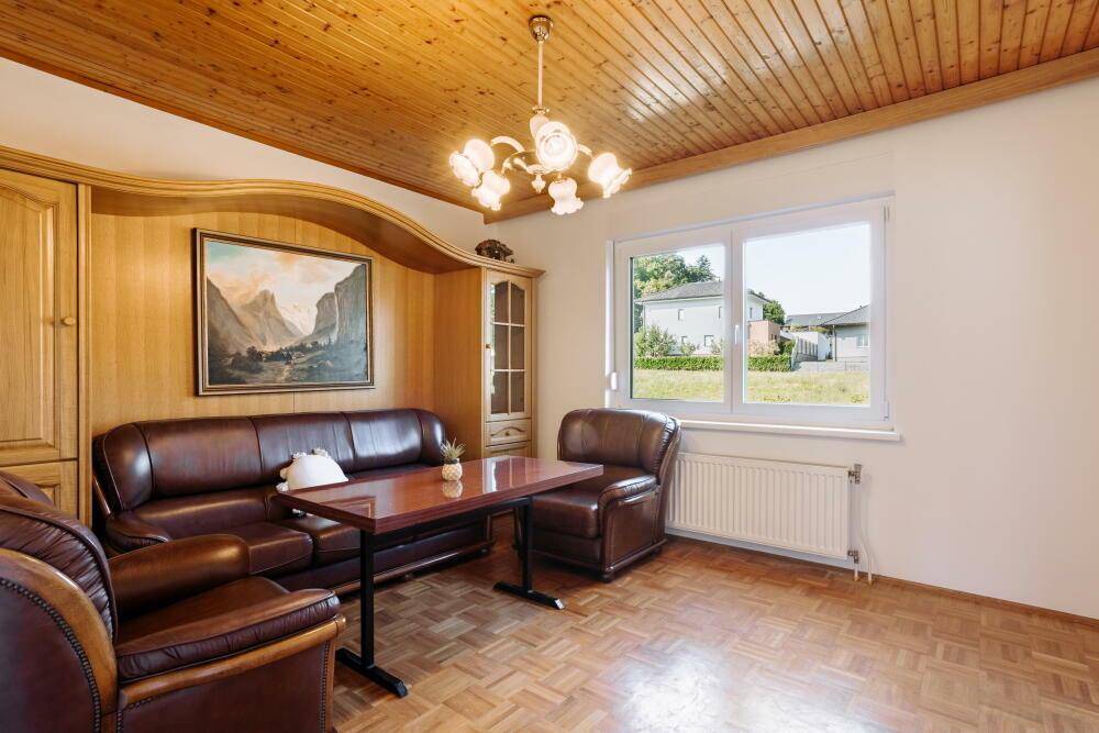 Traditionelles Wohnzimmer mit Holzbalkendecke, Parkettboden und bequemen Ledersofas.