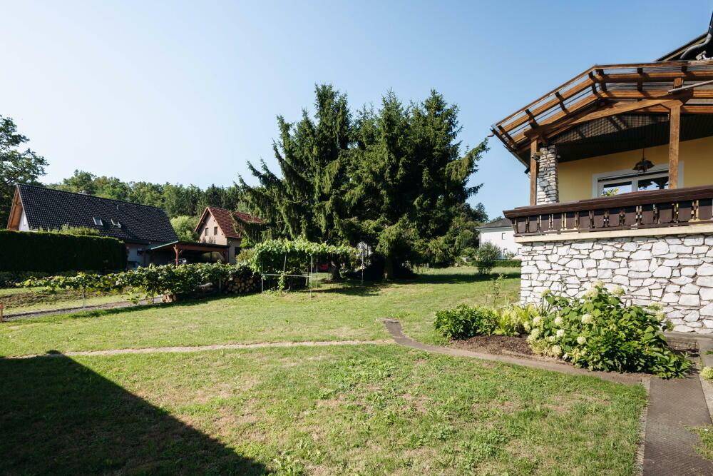 Großer Gartenbereich mit Rasenfläche, alten Bäumen und Blick auf die umliegende Landschaft.