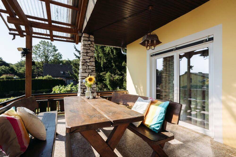 Überdachte Terrasse mit rustikalen Holzmöbeln und weitem Blick ins Grüne.