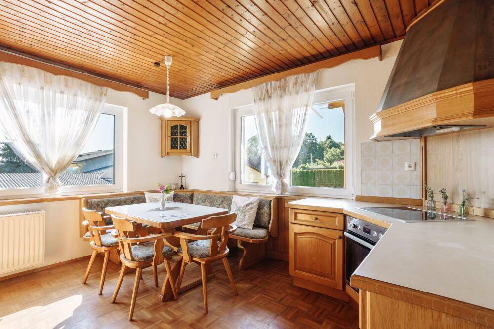 Gemütliche traditionelle Küche mit Holzbalkendecke, Essbereich und Blick in den Garten.