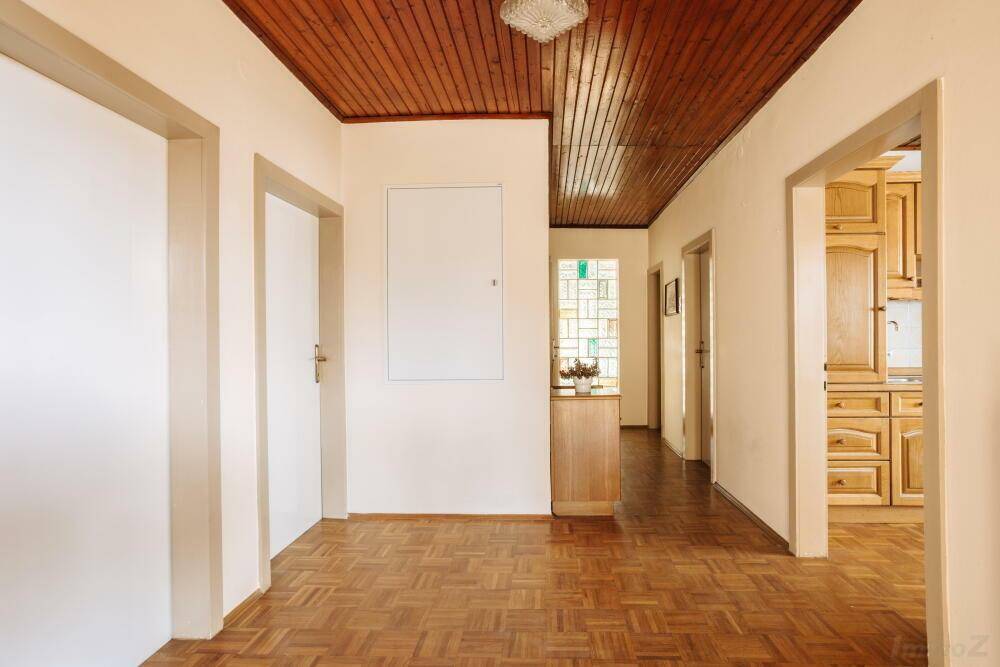 Geräumiger Flur mit Holzbalkendecke, Parkettboden und Zugang zu verschiedenen Zimmern.