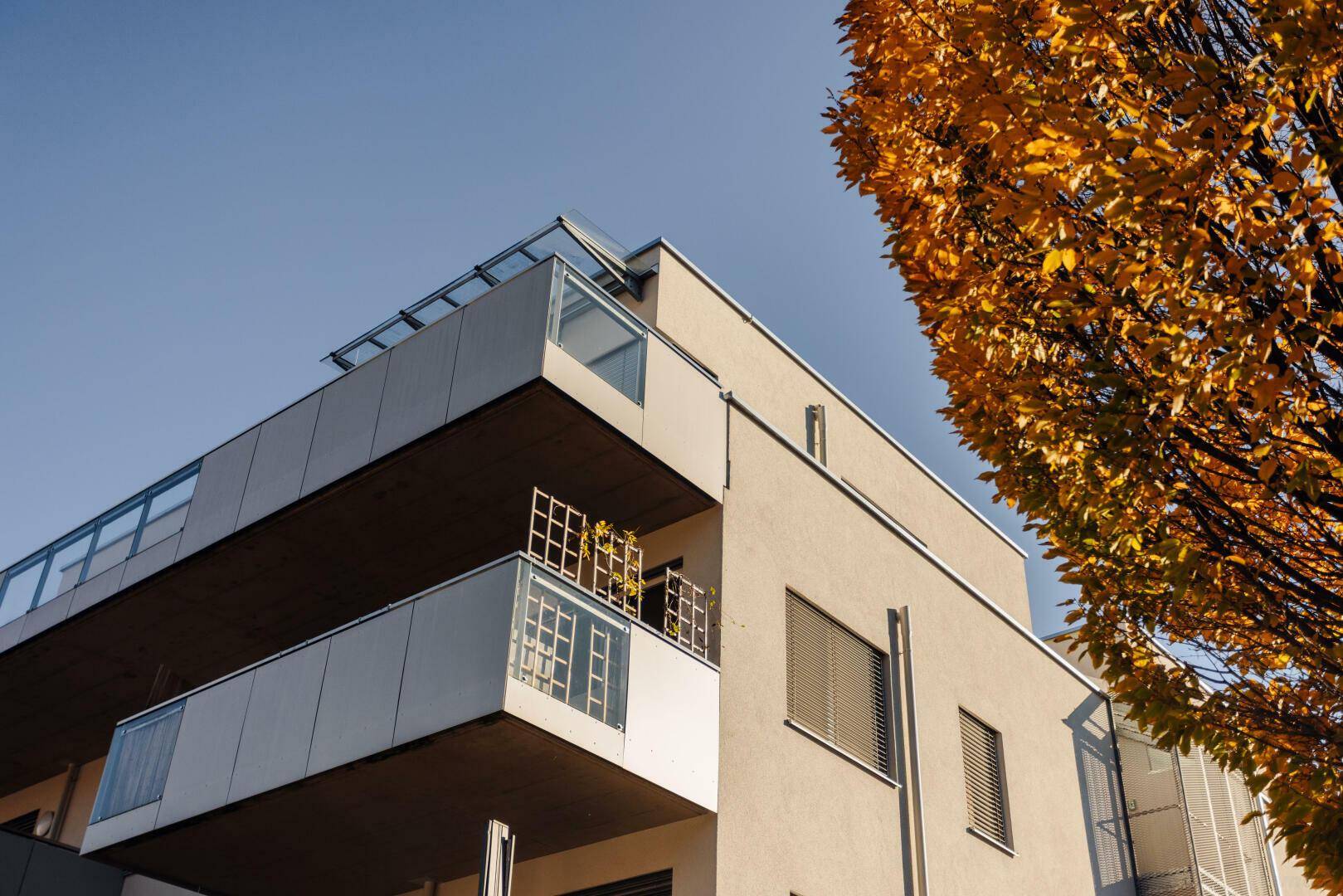 Moderne Architektur des Gebäudes mit Balkonen und großen Fenstern im warmen Herbstlicht.
