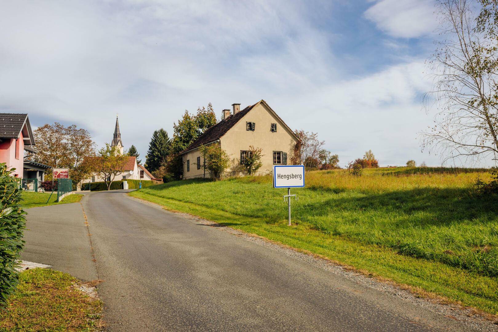 Blick auf eine ländliche Straße mit einem traditionellen Haus und dem Ortsschild 'Hengsberg'.