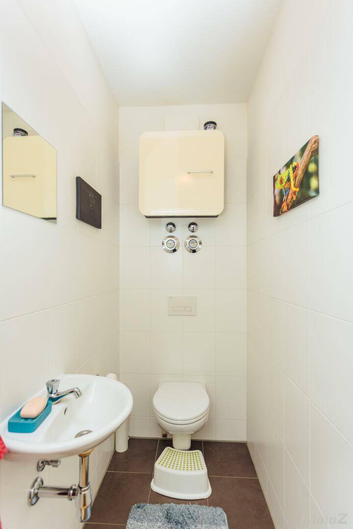 Separates Gäste-WC mit wandhängender Toilette und kleinem Handwaschbecken.