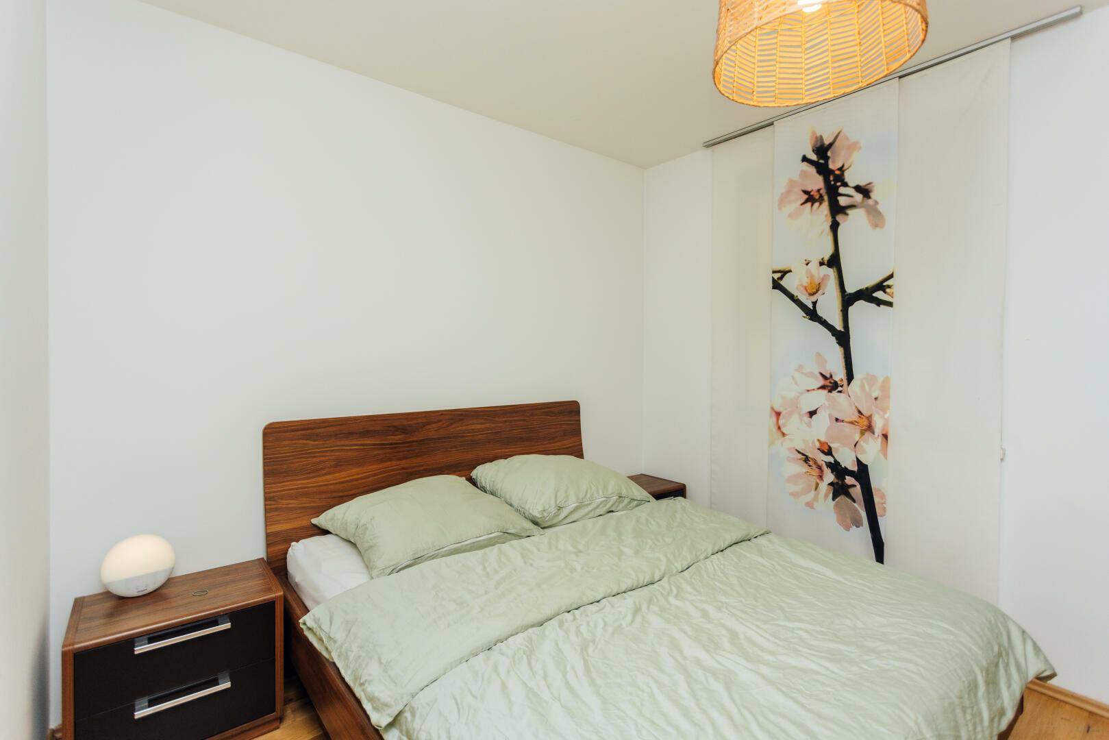 Gemütliches Schlafzimmer mit Holzbett, Nachttischen und heller Wandgestaltung.