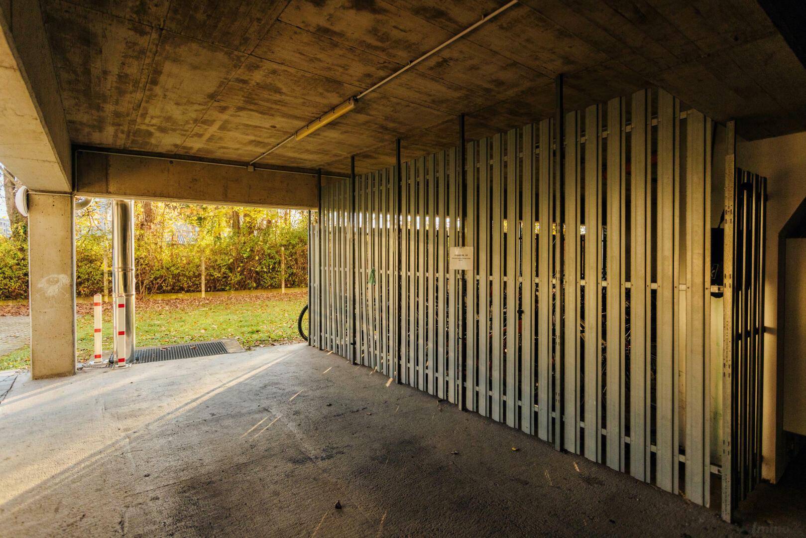 Überdachter Parkbereich mit Fahrradständern und Zugang zum Außenbereich.