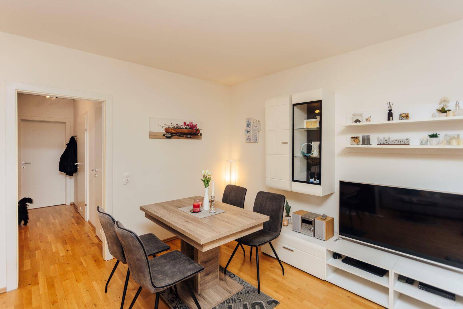 Gemütlicher Wohn- und Essbereich mit Holztisch, Parkettboden und moderner Einrichtung.