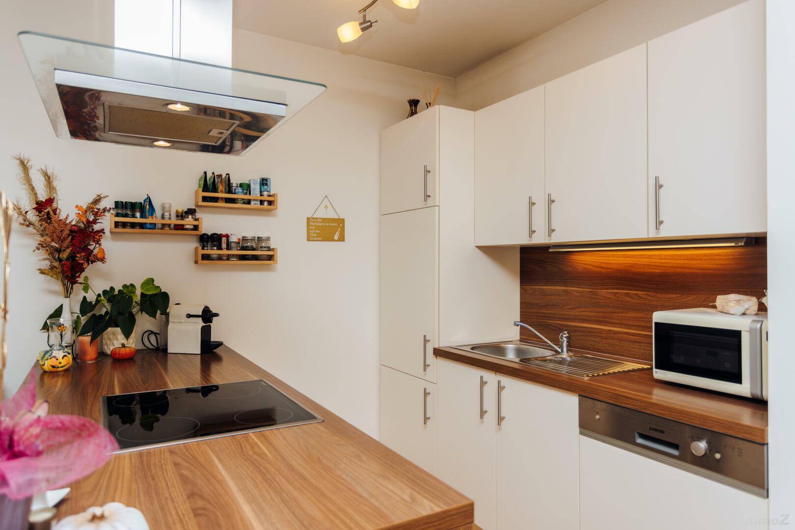 Moderne Einbauküche mit weißen Schränken, Holz-Arbeitsplatten und integrierten Geräten.