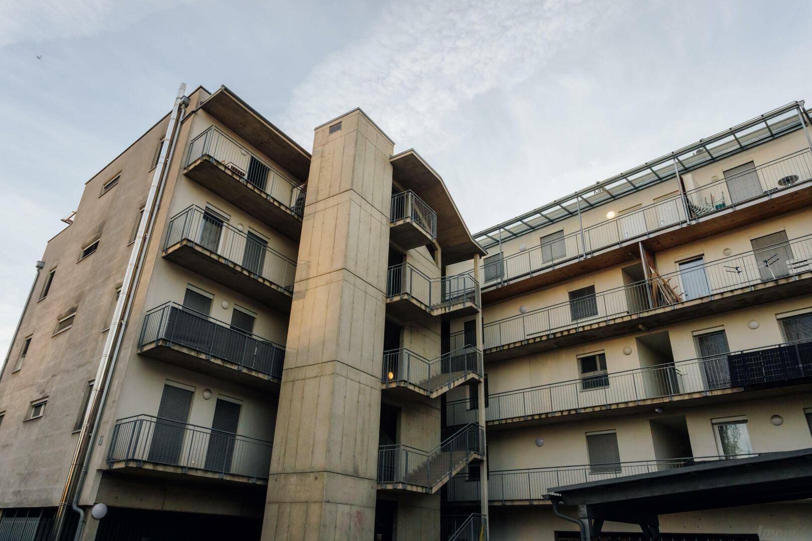 Ansicht eines modernen Mehrfamilienhauses mit Außentreppe und zahlreichen Balkonen.