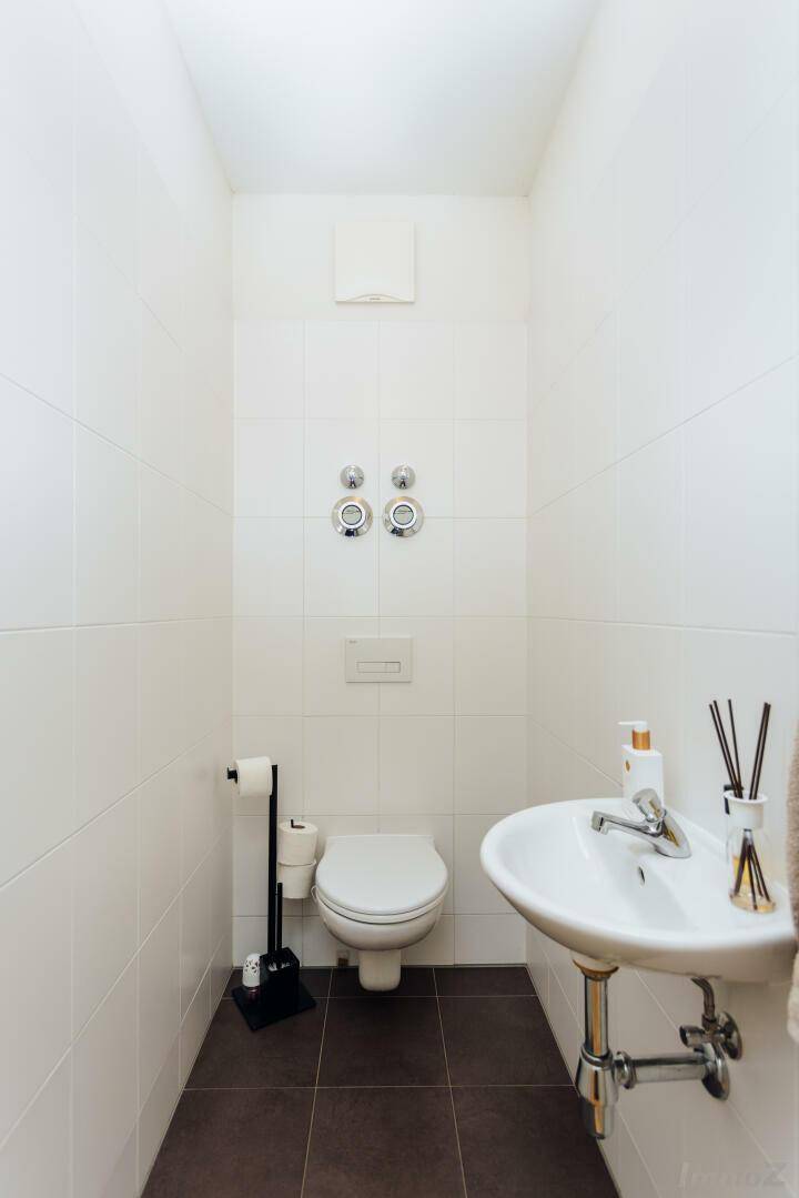 Separates Gäste-WC mit wandhängender Toilette und kleinem Handwaschbecken.