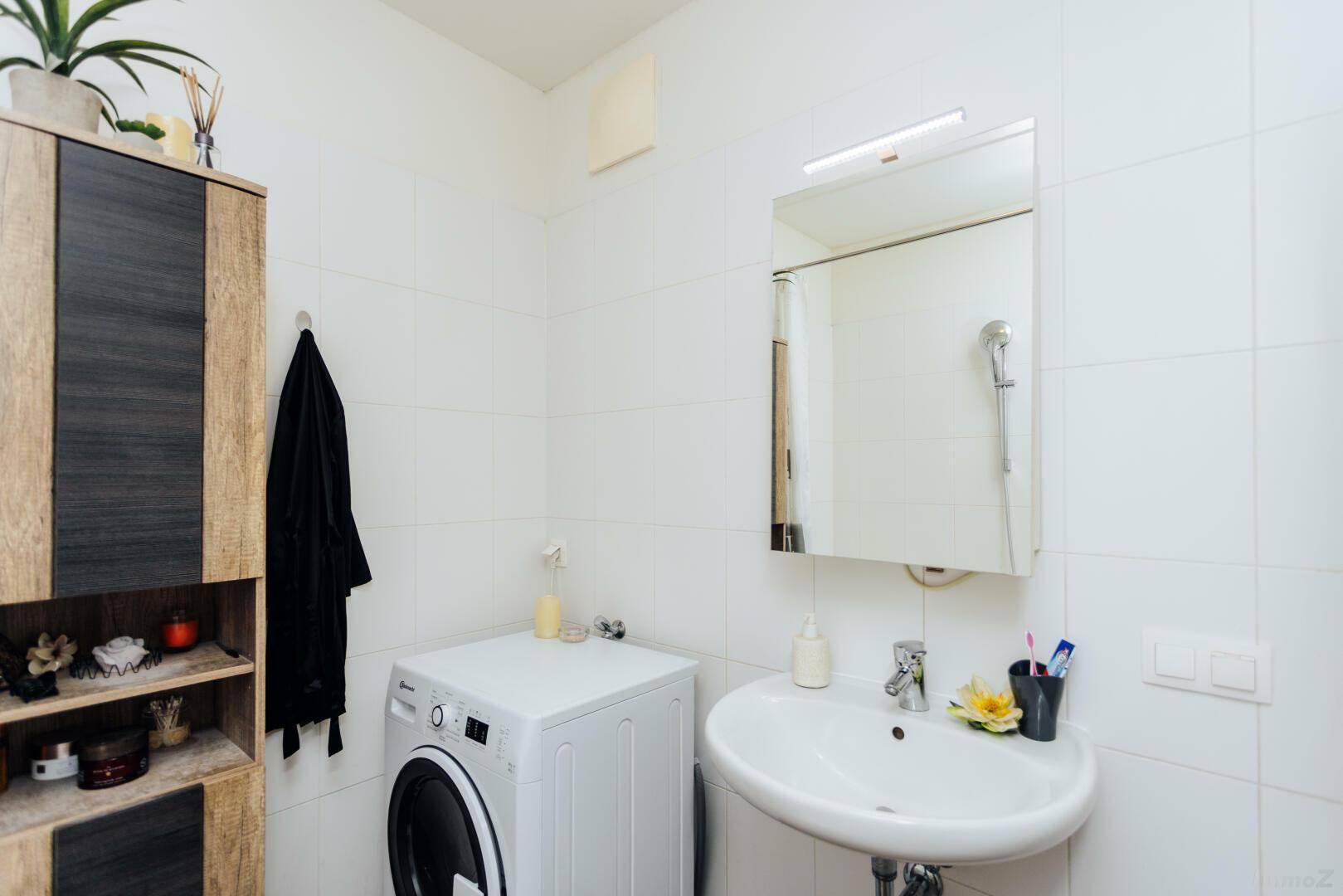 Helles Badezimmer mit Waschbecken, Spiegelschrank und Waschmaschine.