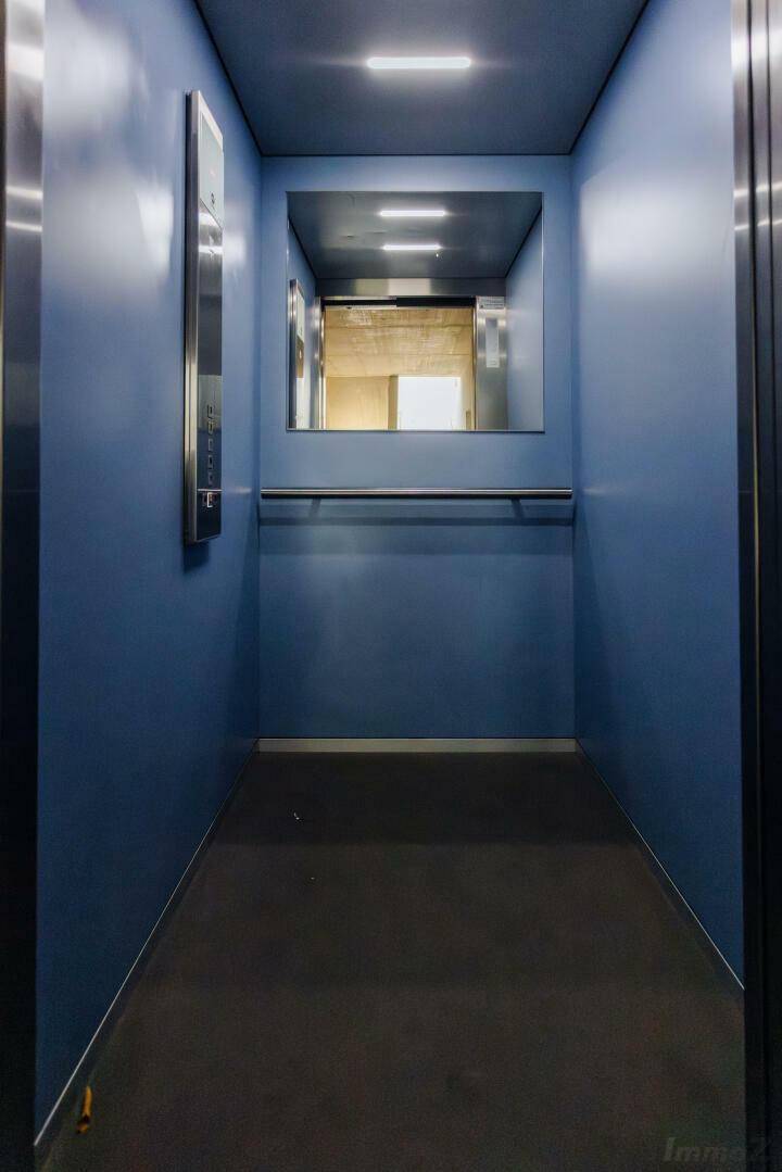Moderner Aufzug mit blauen Wänden und Edelstahl-Elementen, bietet Zugang zu allen Etagen.