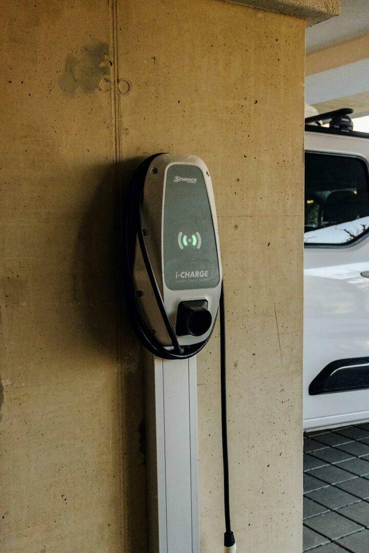 Ladestation für Elektrofahrzeuge an einer Säule im überdachten Parkbereich.