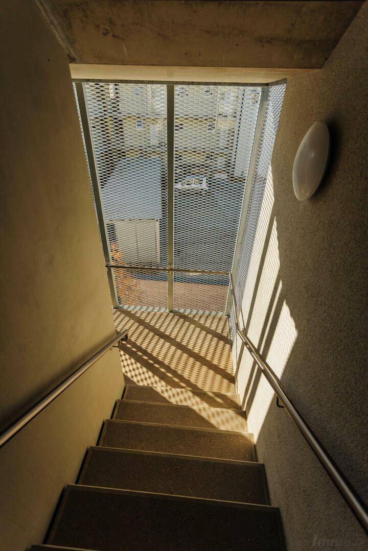 Treppenhaus mit Tageslicht und Metallgeländer, führt zu den oberen Etagen.