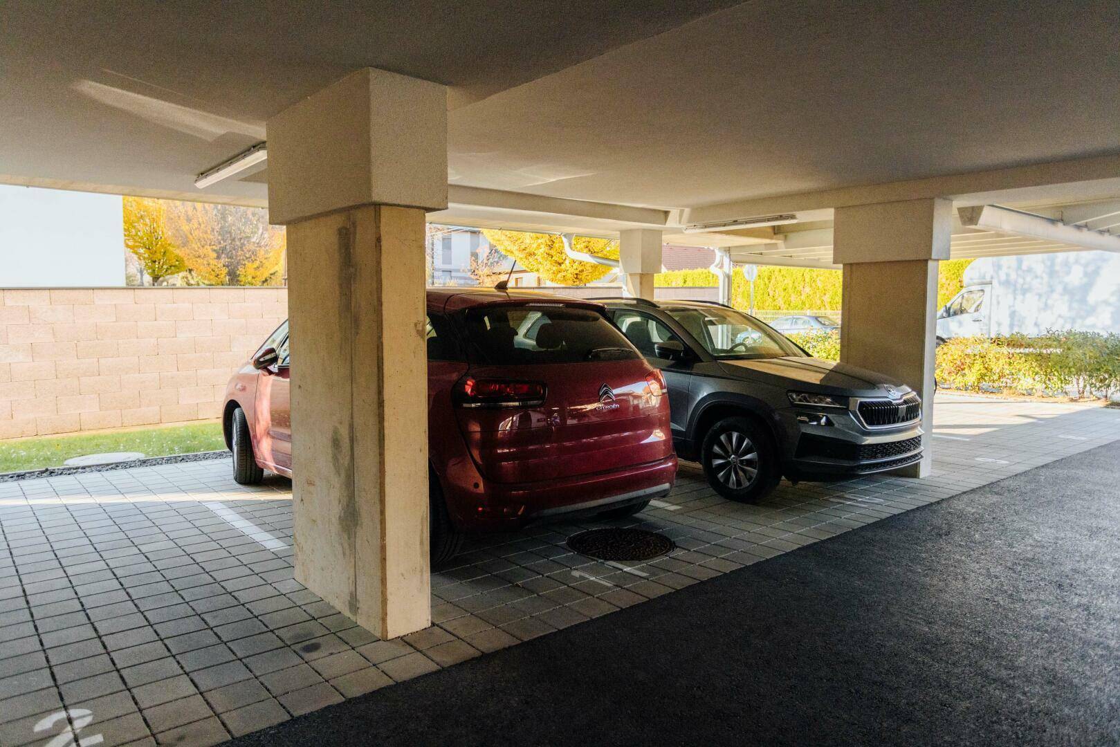 Überdachte Parkplätze für mehrere Fahrzeuge mit gepflastertem Boden.