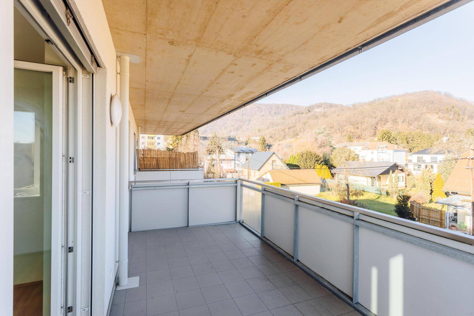 Großer Balkon mit Fliesenboden und Blick auf die umliegende Hügellandschaft und Häuser.