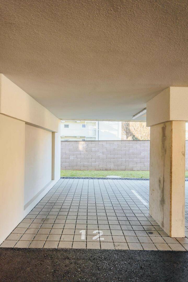 Überdachter Parkplatz mit nummerierter Stellfläche und gepflastertem Boden.