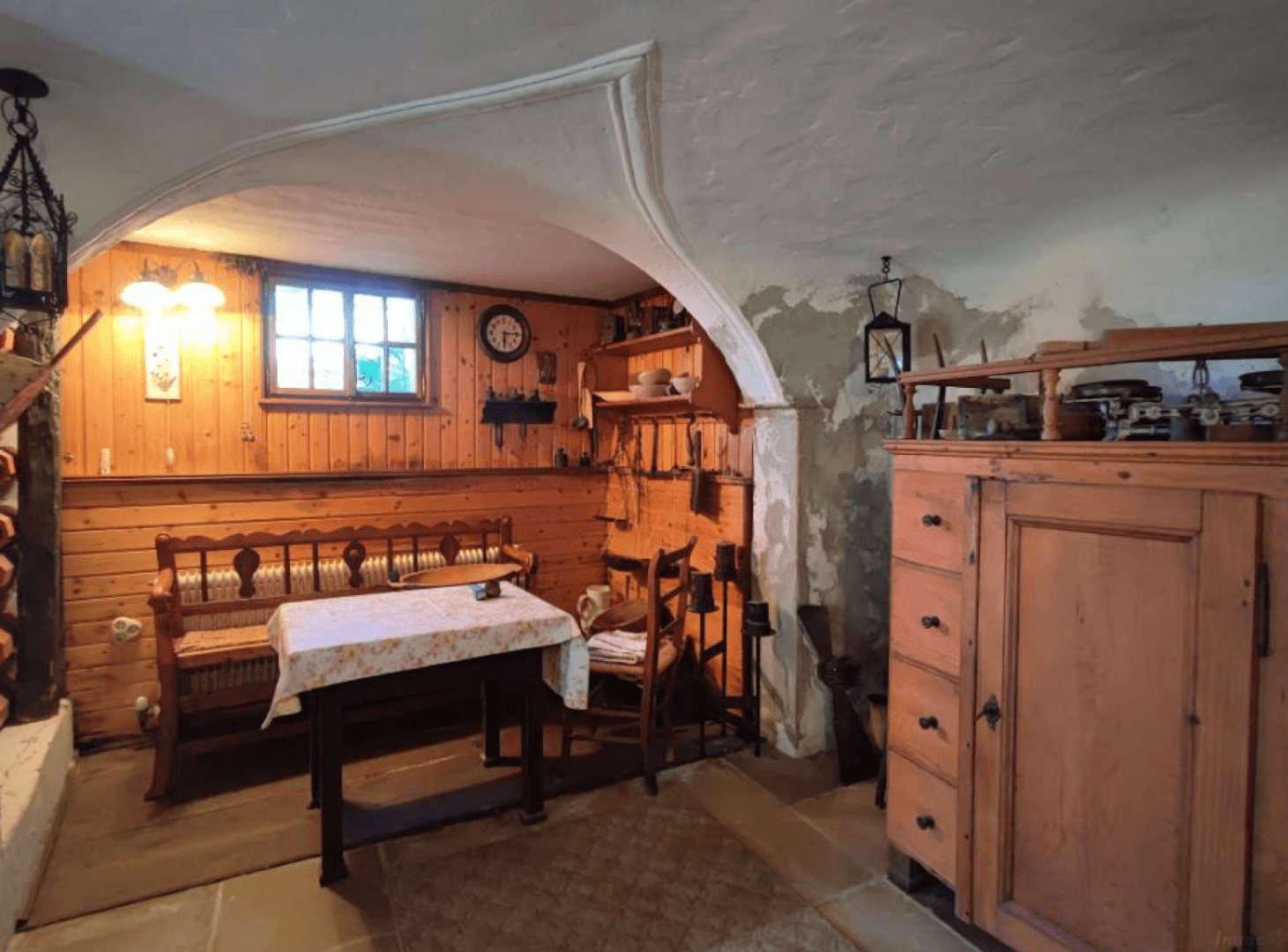 Rustikaler Kellerraum mit Holztäfelung, gewölbter Decke und traditionellen Möbeln.