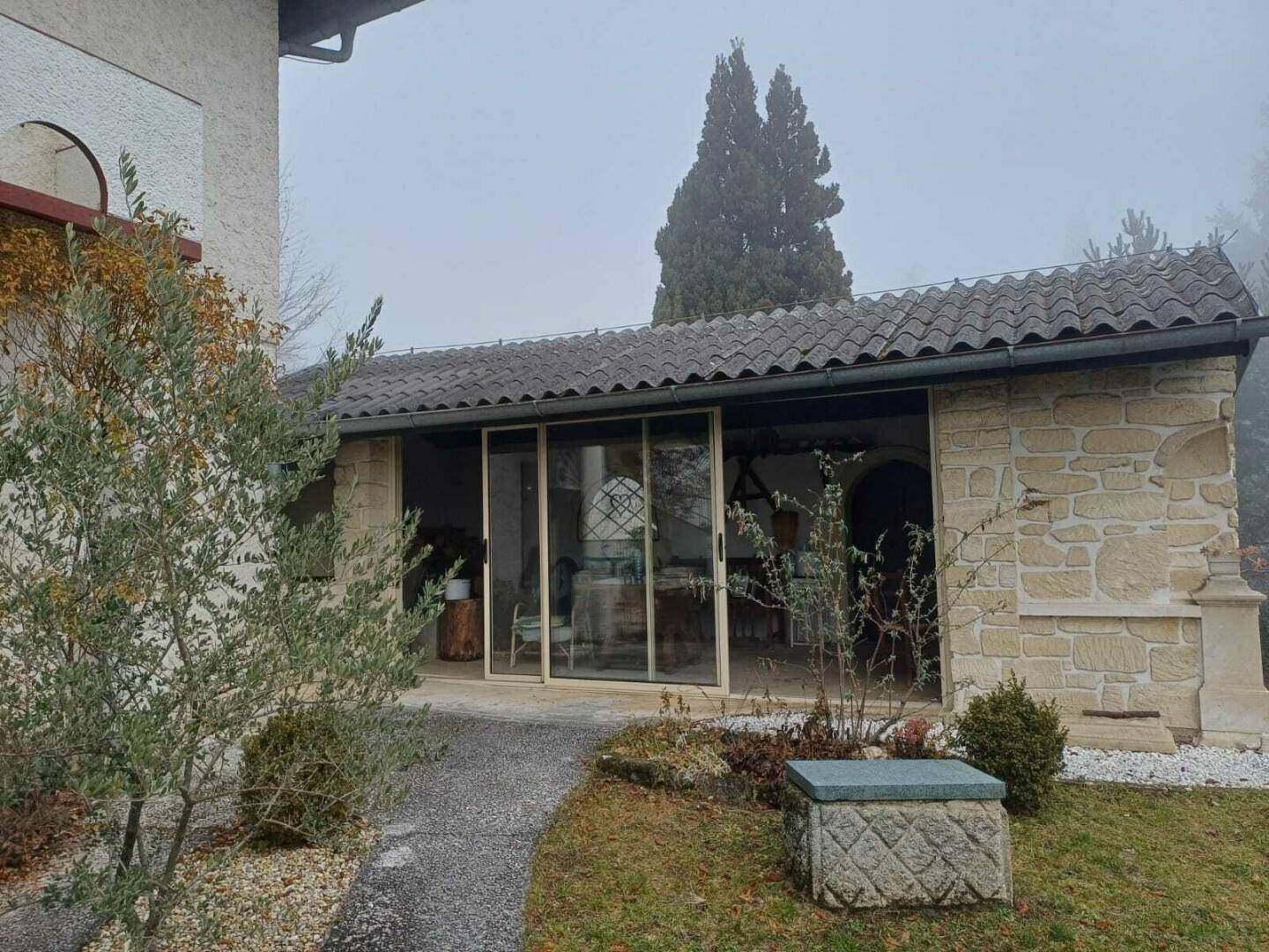 Überdachte Terrasse mit Steinmauern und Zugang zu einem hellen Innenbereich.