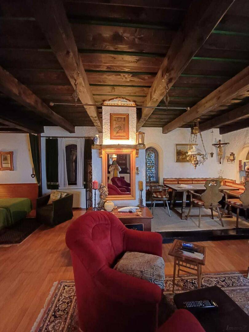 Traditionelles Wohnzimmer mit dunklen Holzbalken, roten Sesseln und einem großen Spiegel.
