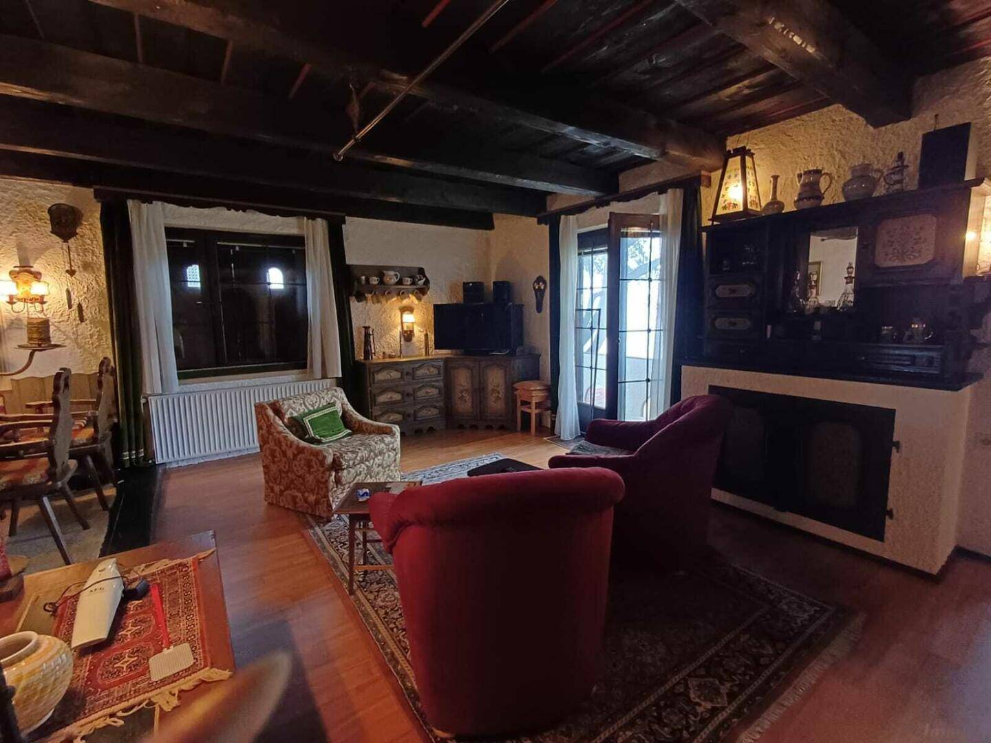 Gemütliches Wohnzimmer mit dunklen Holzbalken, Kamin und traditionellen Möbeln.