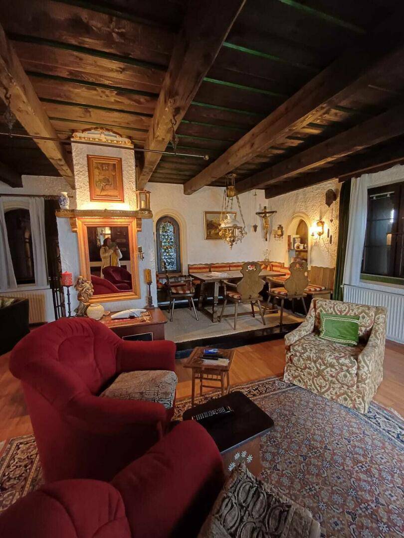 Gemütliches Wohnzimmer im alpinen Stil mit Holzbalkendecke, Kamin und traditionellen Möbeln.
