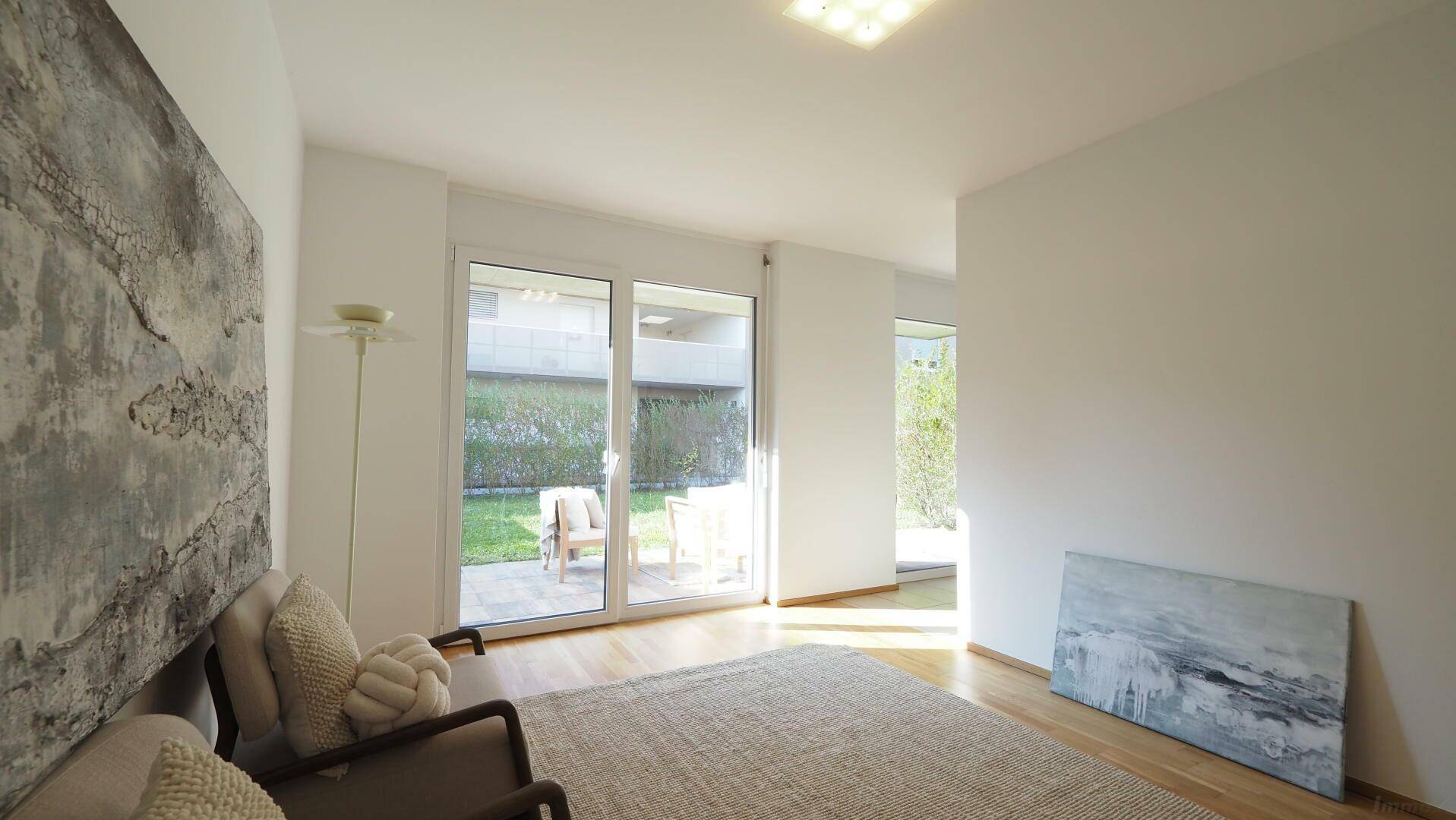 Geräumiges Wohnzimmer mit Holzboden und Blick auf den grünen Gartenbereich.