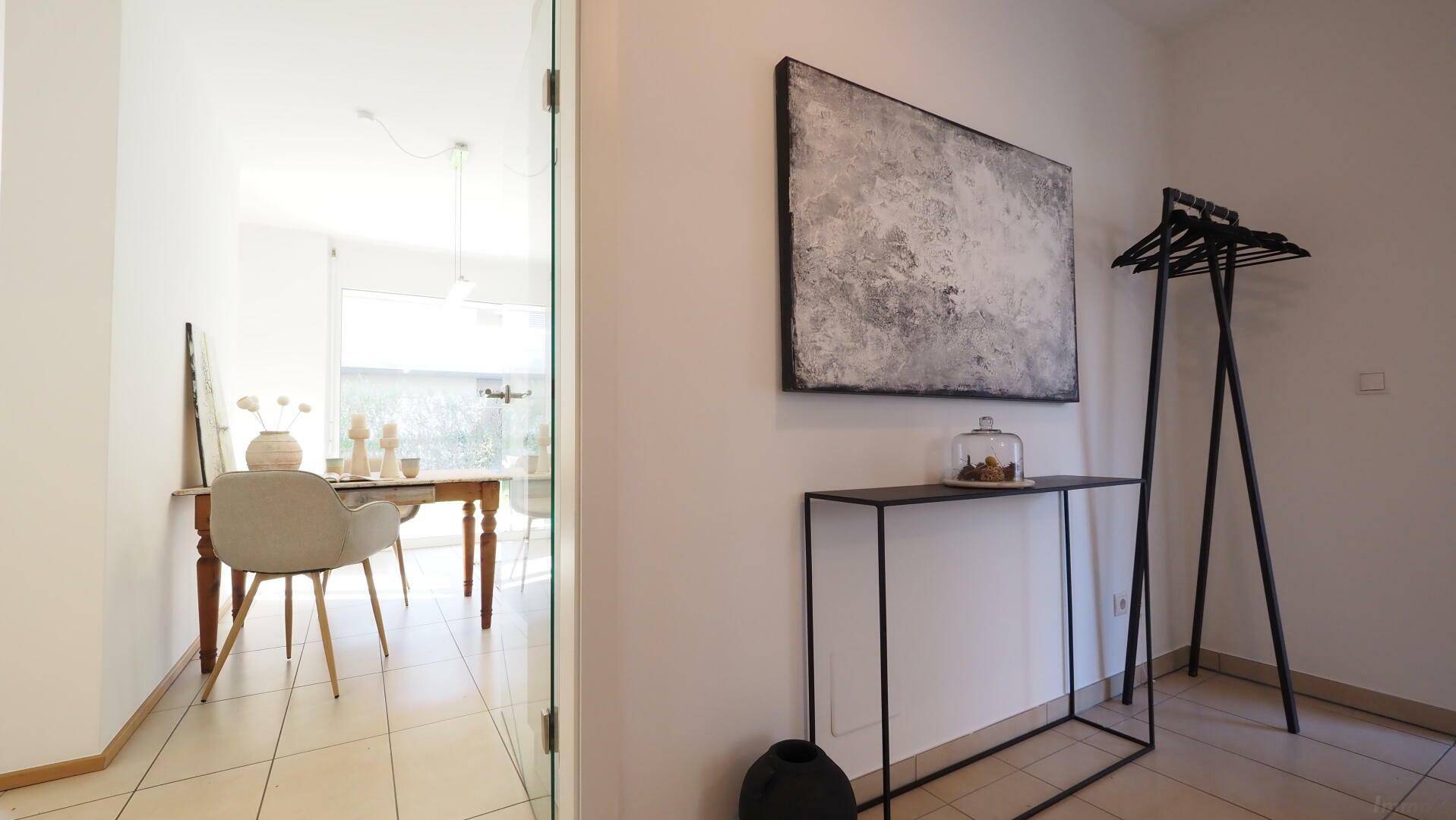 Eingangsbereich mit Fliesenboden und moderner Einrichtung, Blick in den hellen Essbereich.