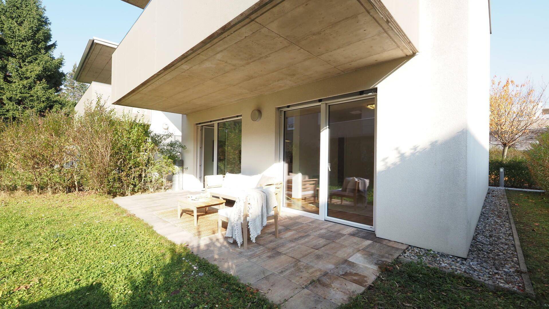 Sonniger Gartenbereich mit gepflasterter Terrasse und direktem Zugang zum Haus.