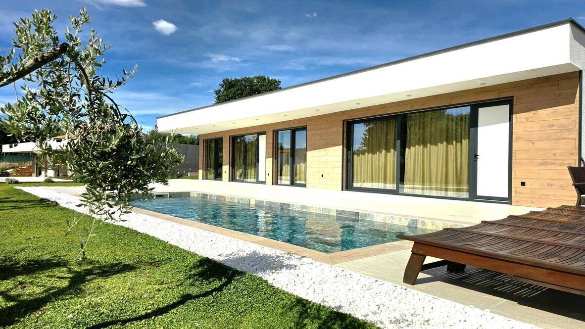 Sonnenverwöhnter Außenbereich mit Pool, Liegestuhl und mediterraner Bepflanzung.