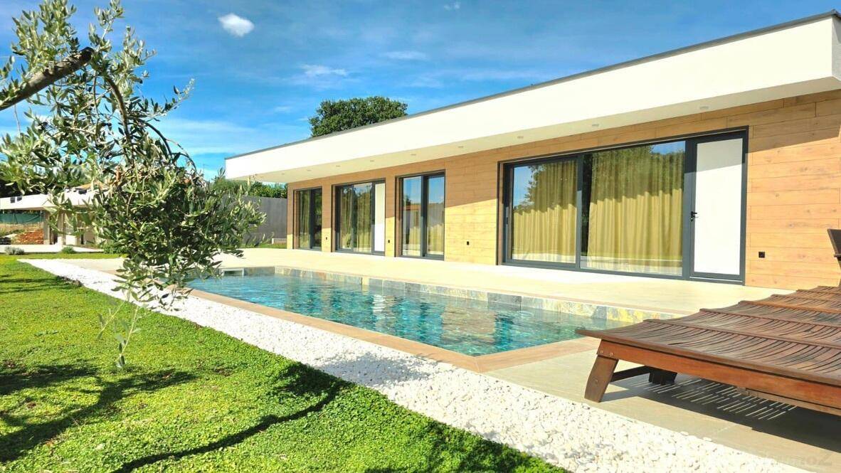 Sonnenverwöhnter Außenbereich mit Pool, Liegestuhl und mediterraner Bepflanzung.