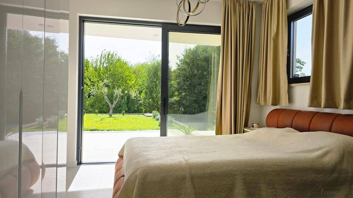 Helles Schlafzimmer mit großem Bett, raumhohen Fenstern und direktem Zugang zum Garten.