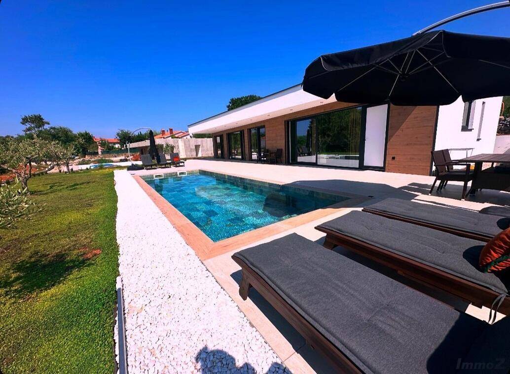 Großer Außenbereich mit modernem Pool, Sonnenliegen und Essbereich im Freien.
