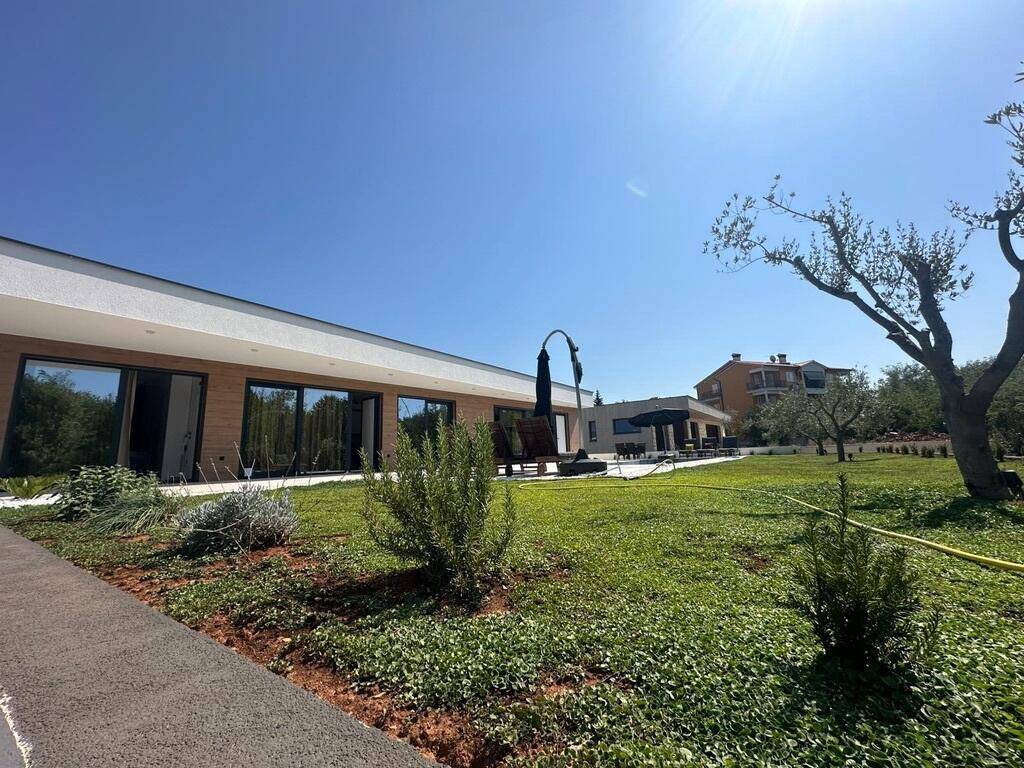 Moderne Architektur der Villa mit weitläufigem Garten und mediterraner Bepflanzung.