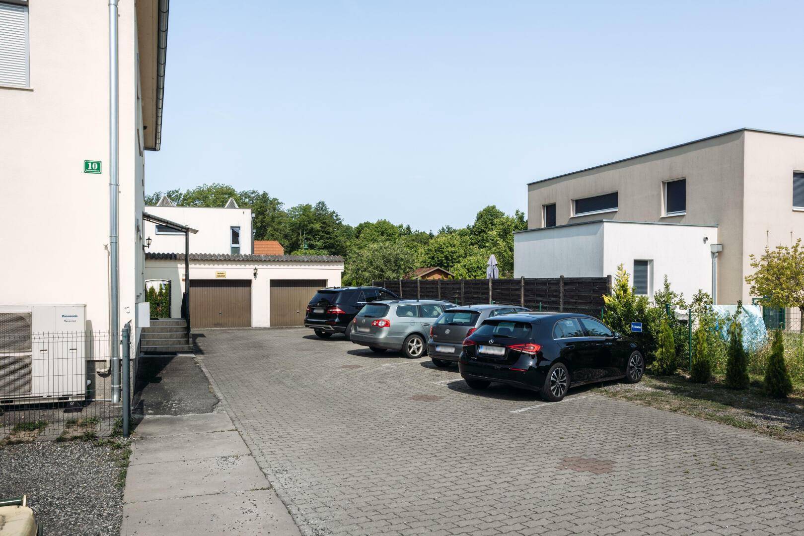 Außenbereich mit mehreren Parkplätzen und Garagen für Fahrzeuge.