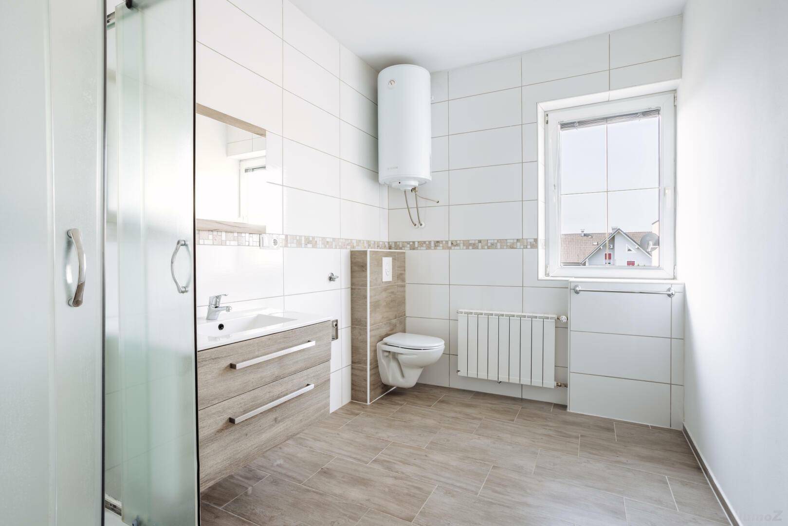 Helles Badezimmer mit Fenster, wandhängendem WC und Duschkabine.
