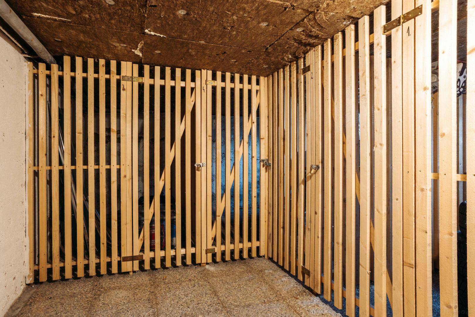 Abgetrennte Lagerbereiche im Keller mit Holzlattenverschlägen.