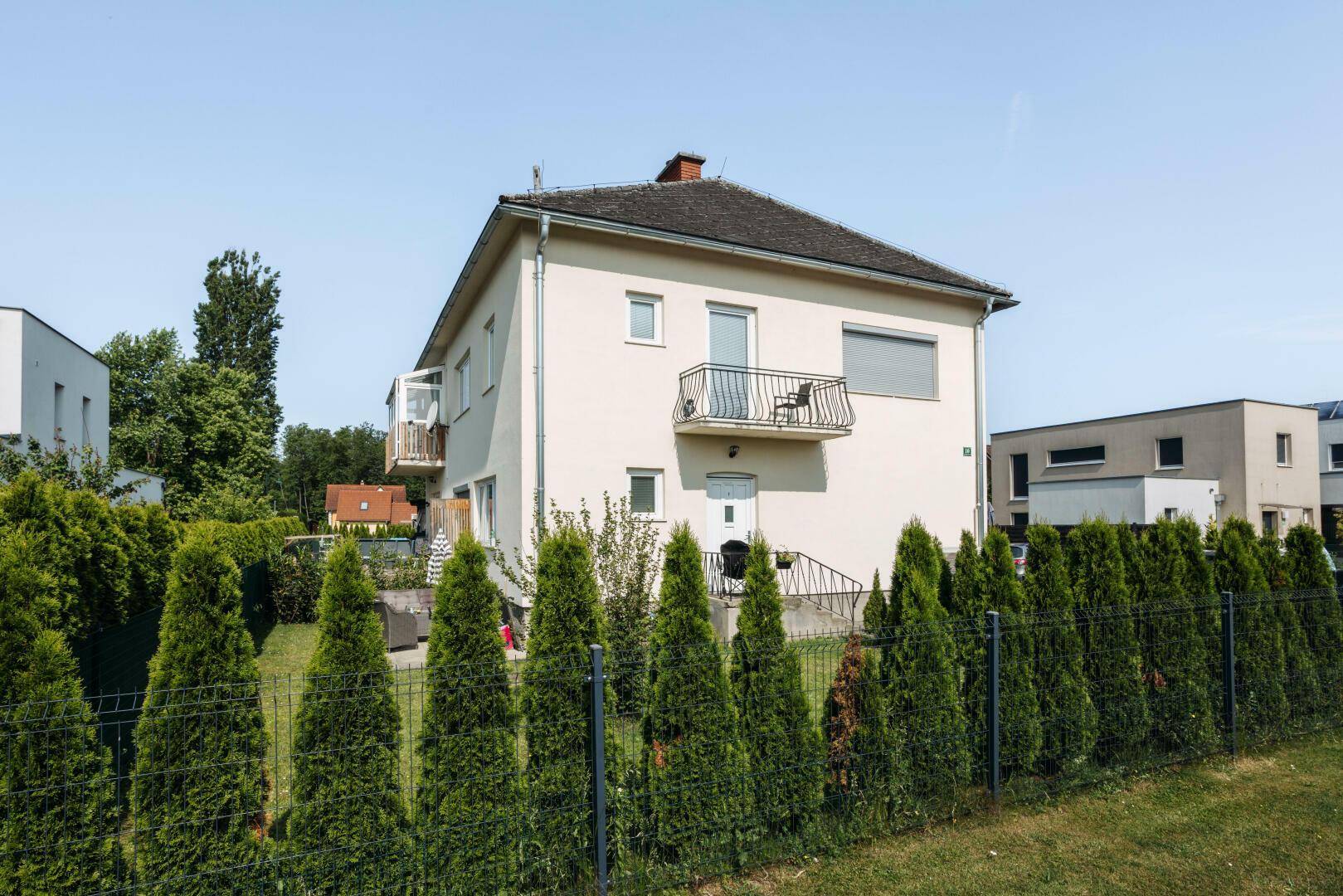 Wohnhaus mit gepflegtem Vorgarten, Zaun und Blick auf die umliegende Wohnsiedlung.
