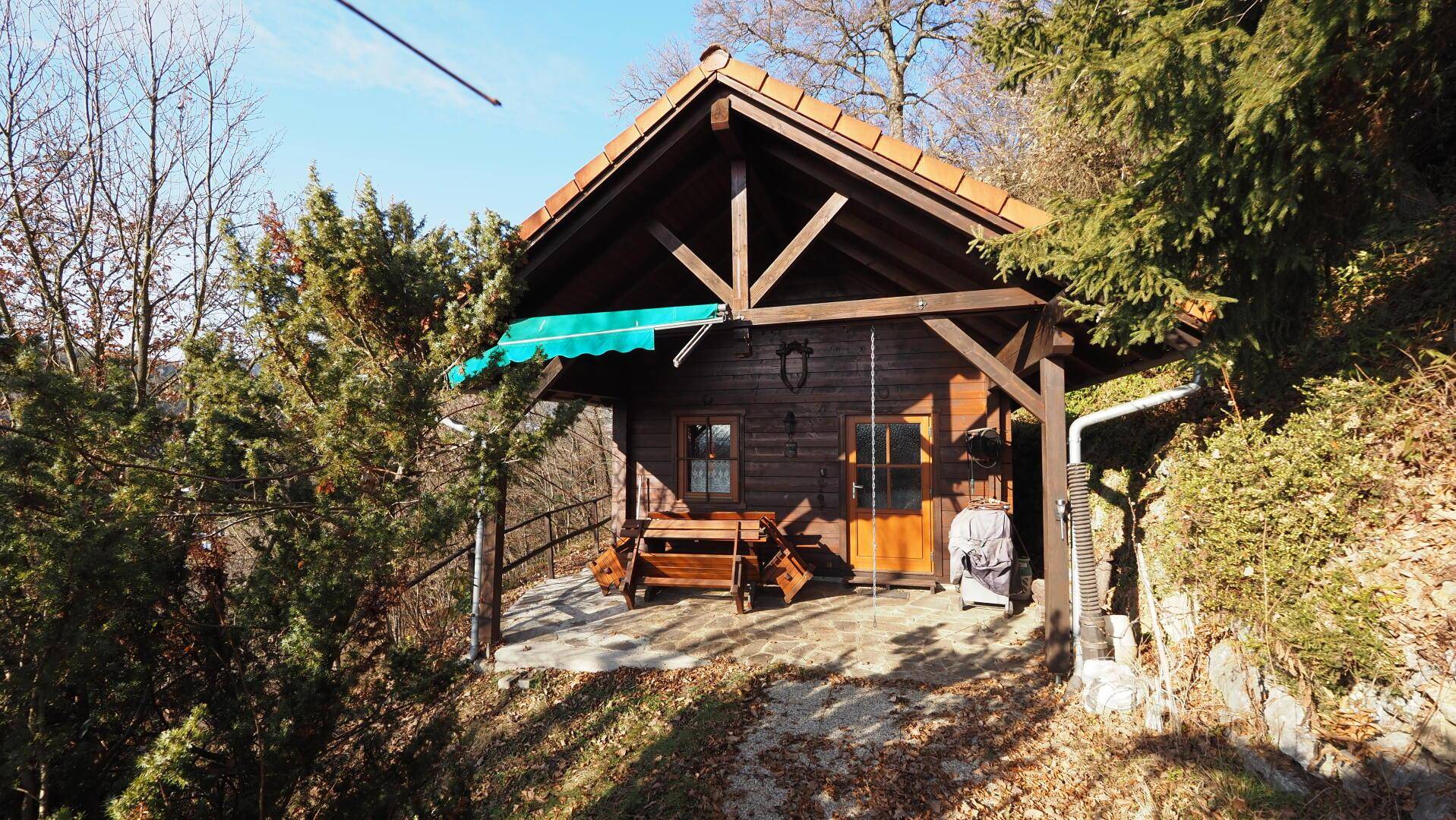 Charmantes Holzchalet mit Satteldach, überdachtem Eingangsbereich und umgebender Natur.