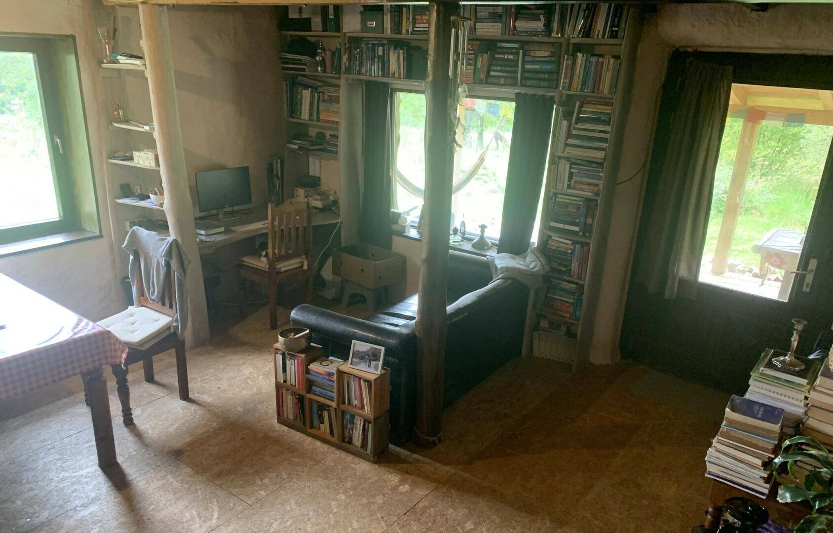 Wohnbereich mit vielen Büchern, einem Schreibtisch und Zugang zu einem Außenbereich.