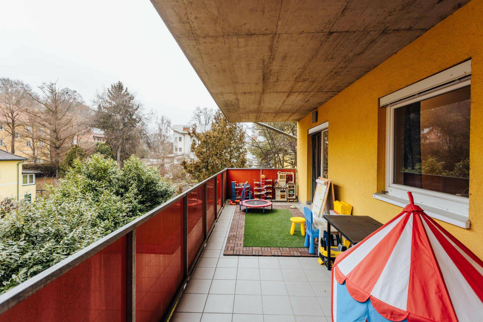 Geräumiger Balkon mit Spielbereich, Kunstrasen und Blick ins Grüne, ideal für Familien.