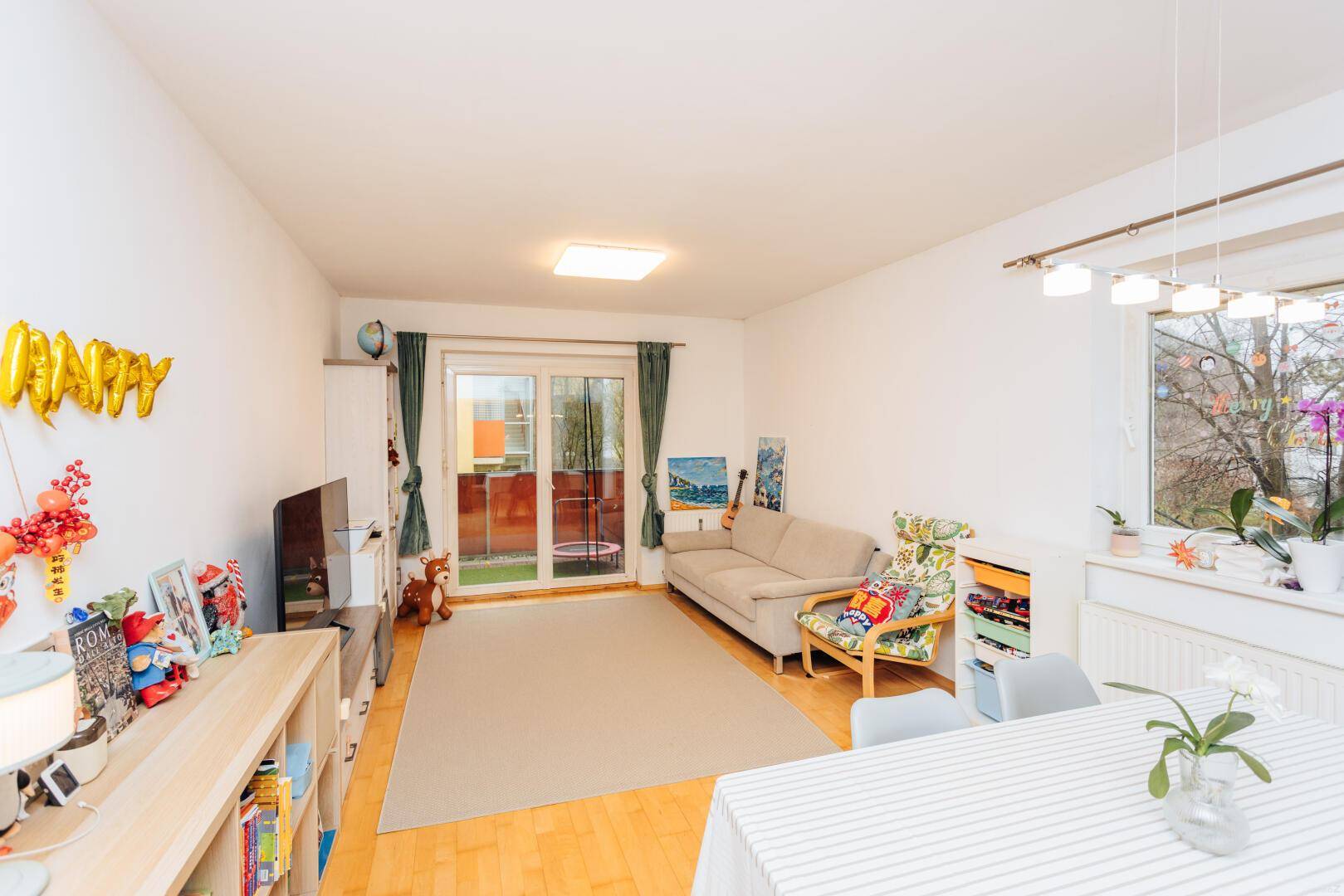 Gemütliches Wohnzimmer mit Sofa, Fernseher und direktem Zugang zu einem Balkon.