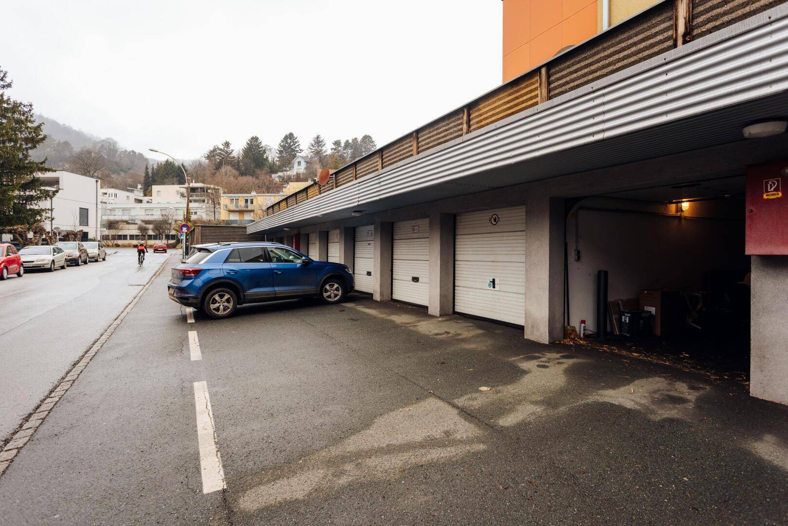 Reihe von Garagenboxen entlang einer Straße mit zusätzlichen Außenparkplätzen.